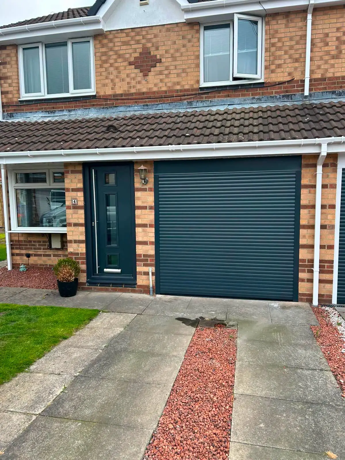 Dark roller garage door and matching composite front door installed by Window Warriors
